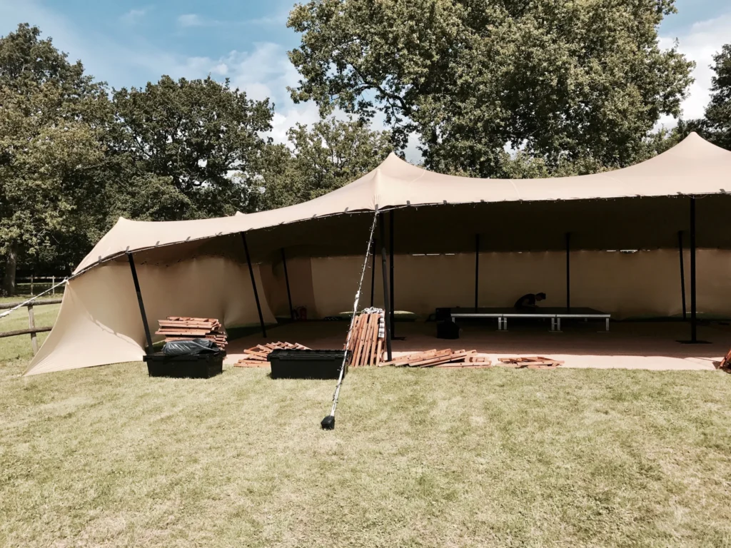 Outdoor event setup in a large garden with marquee tents, speakers, and technician preparing equipment in the West Midlands
