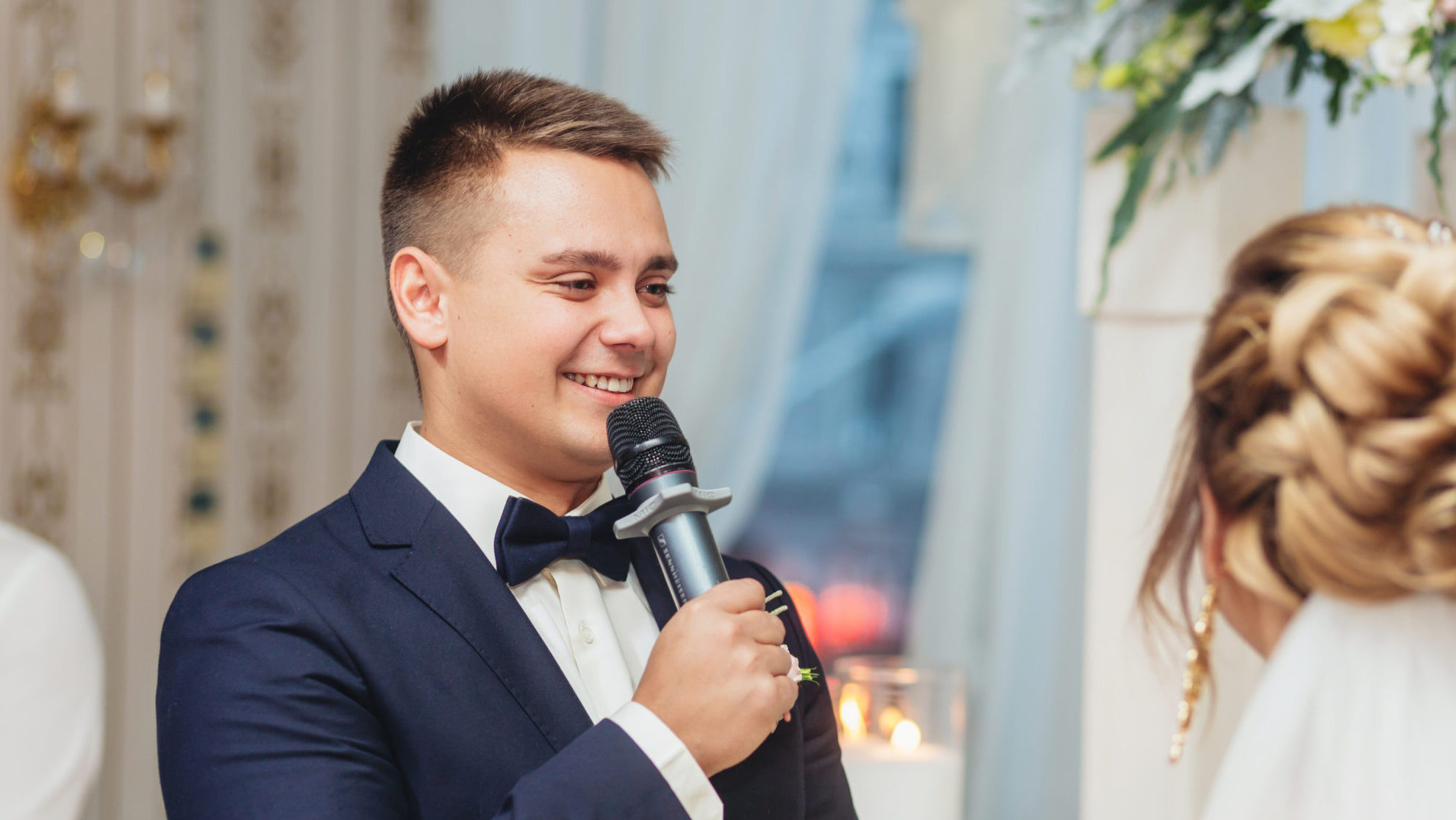 Groom speaking into a wireless microphone during a wedding ceremony, showing practical use in live, mobile events