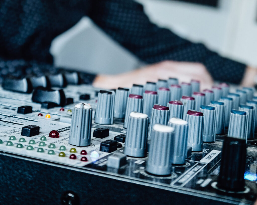 Close-up of an audio mixer with hands adjusting knobs during an event setup