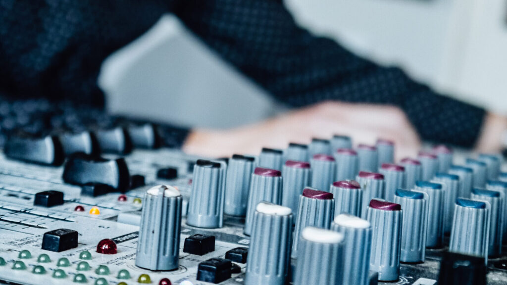 Close-up of an audio mixer with hands adjusting knobs during an event setup
