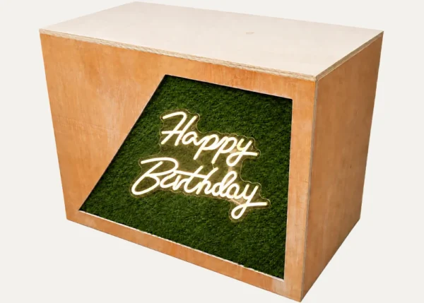 Rustic DJ booth with Happy Birthday neon sign and green foliage front panel