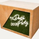 Rustic wooden DJ booth with Till Death Do Us Party neon sign and grass front panel