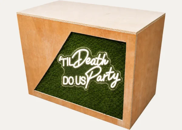 Rustic wooden DJ booth with Till Death Do Us Party neon sign and grass front panel