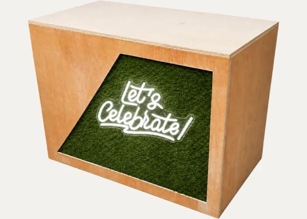 Rustic DJ booth with Let’s Celebrate neon sign and green grass-style front panel