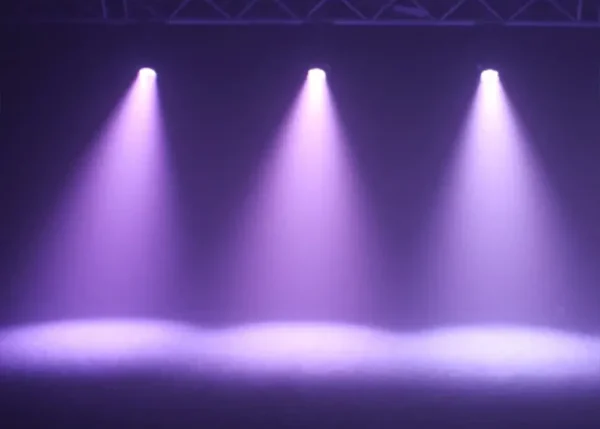 Purple stage spotlights shining through haze for event lighting and performance setups
