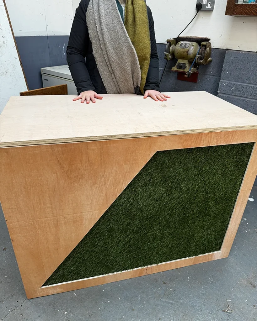 Custom exhibition stand build in progress with artificial grass feature panel