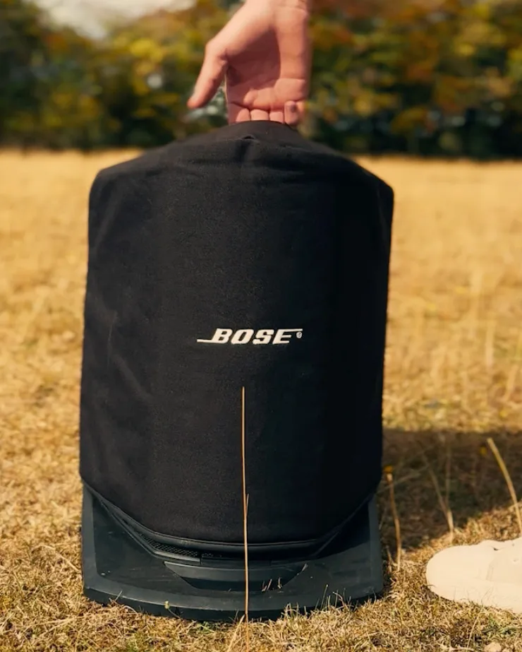 Bose speaker in a protective cover being carried across a field for outdoor event sound hire