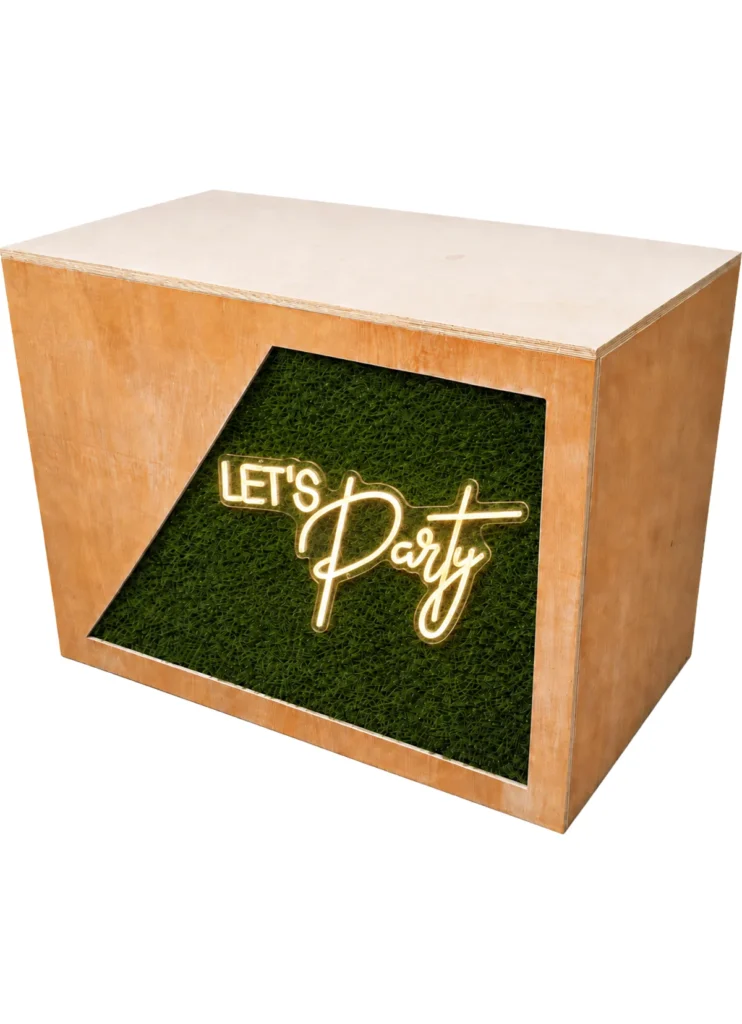 Wooden DJ booth with green foliage panel and illuminated Let’s Party sign for event hire setup