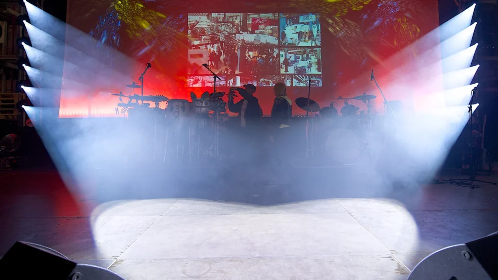 White Chauvet Intimidator Spot 350 beams cutting through smoke across a live event stage
