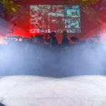 White Chauvet Intimidator Spot 350 beams cutting through smoke across a live event stage
